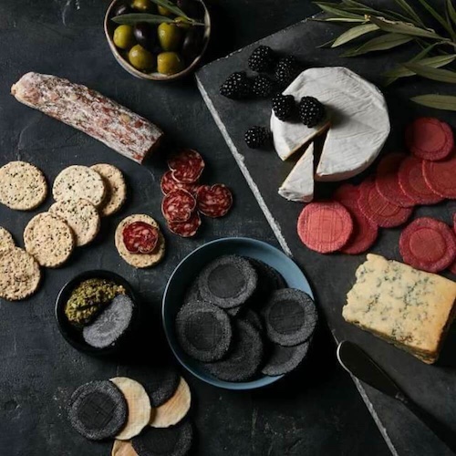 Thin lizies wafer crackers on lavish cheese and charcuterie spread